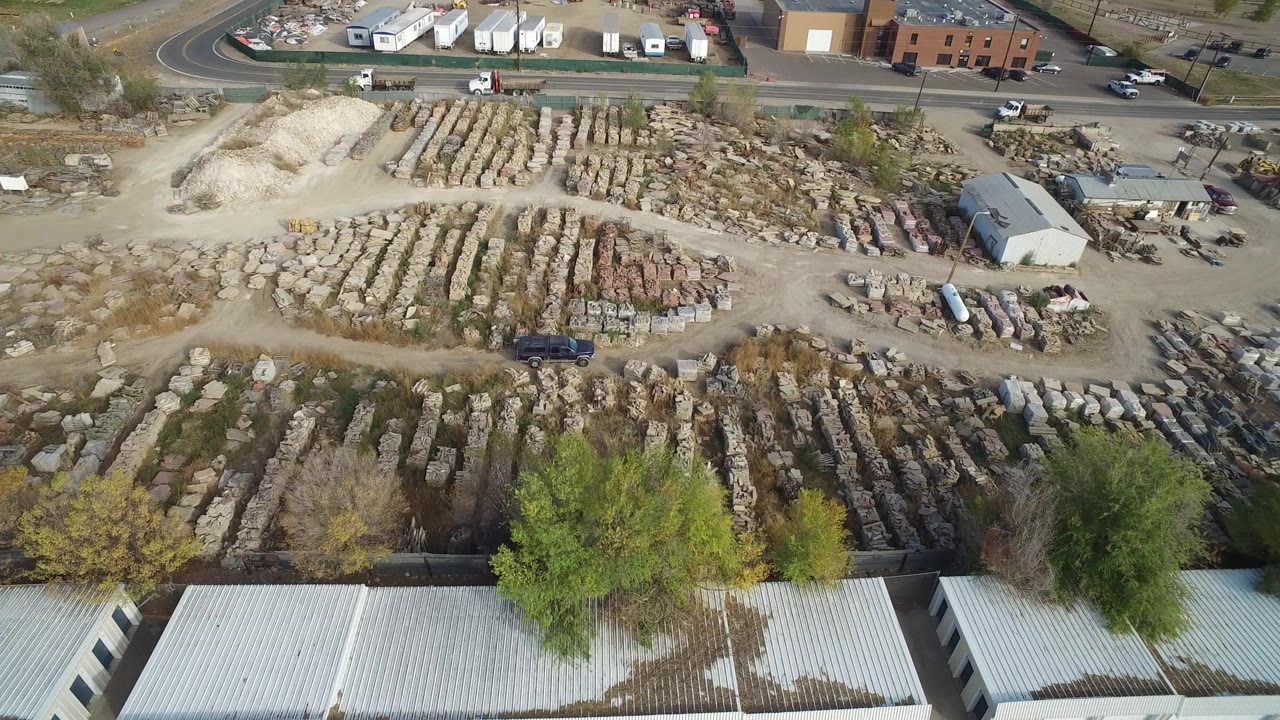 Aerial view of a stone yard beside a road and industrial buildings.