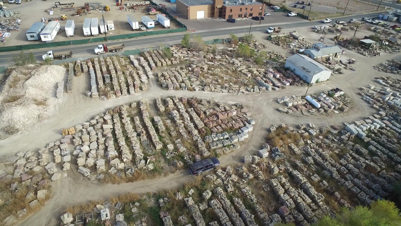Aerial view of an industrial yard with stacked materials and dirt roads.