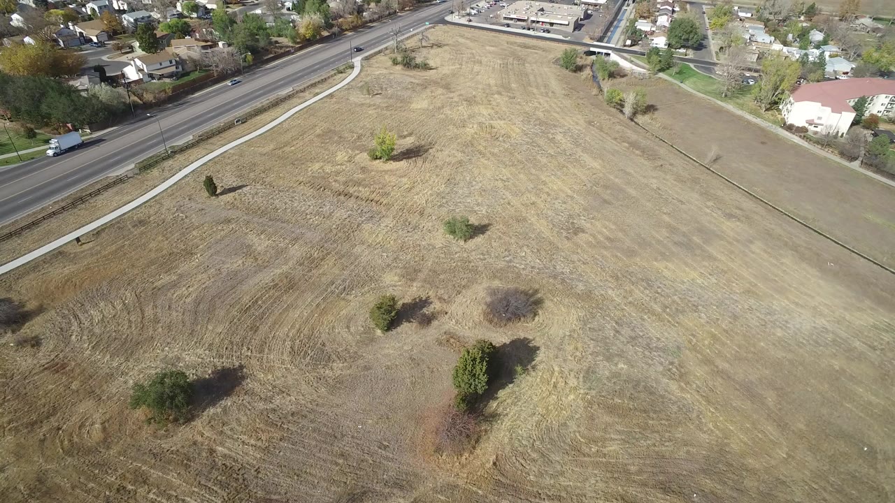 Aerial view of dry field beside a road and houses.