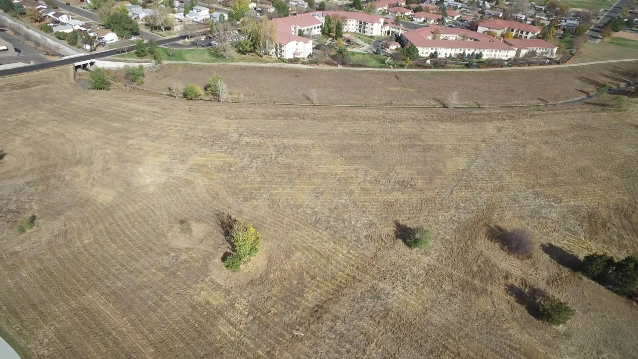 Aerial view of a dry field beside homes and a road.