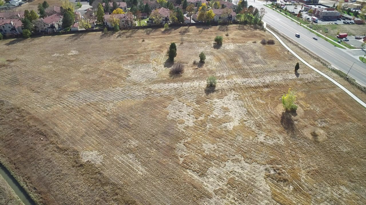 Aerial view of a dry open field beside a residential road.