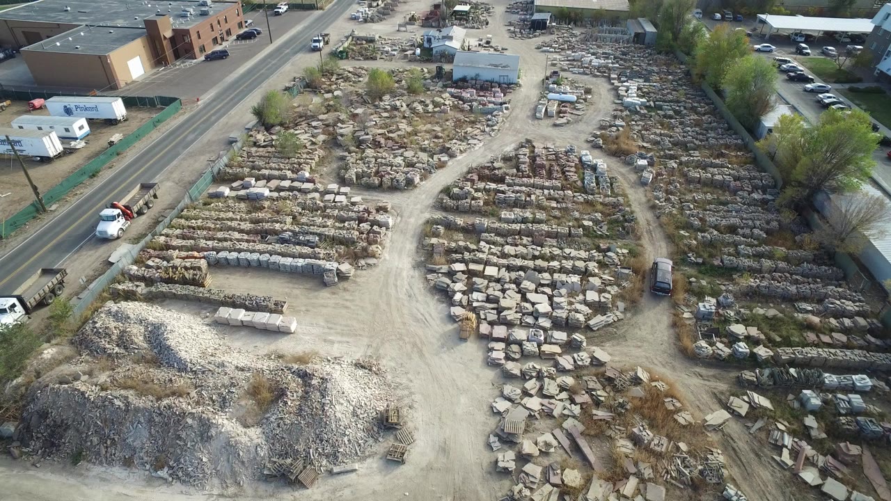 Aerial view of a materials yard beside a road and industrial buildings.