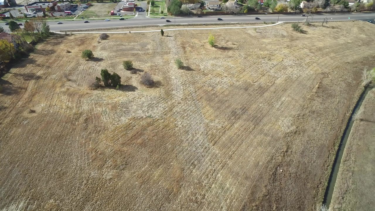 Aerial view of dry fields beside a road and homes