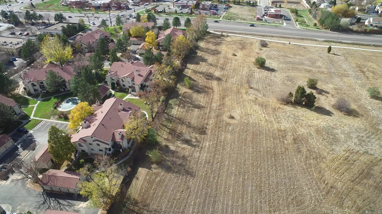 Aerial view of red-roofed buildings beside a dry field and road.