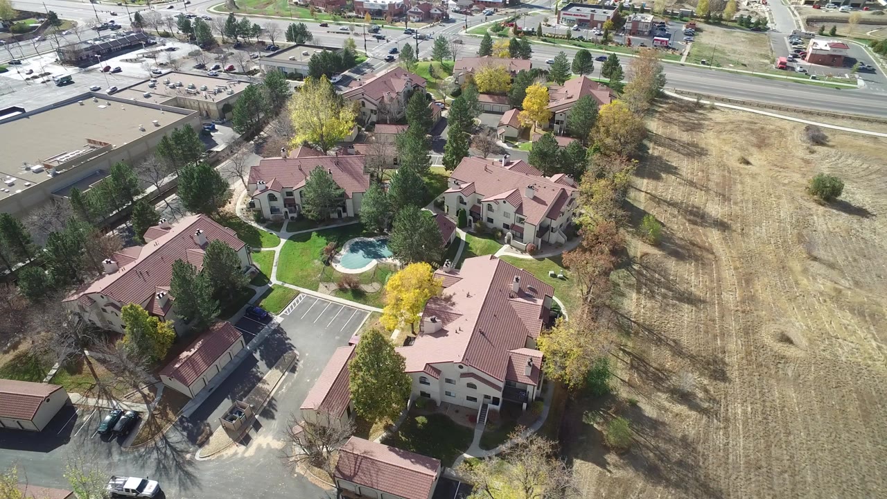 Aerial view of red-roofed residential buildings beside a dry field and road.
