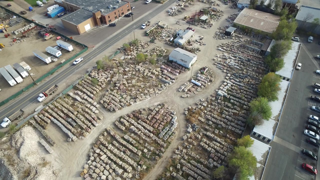 Aerial view in Hidden Lake, Colorado with the central storage yard spread below, a paved road across the upper frame, white trucks and cars near buildings, and no visible people.
