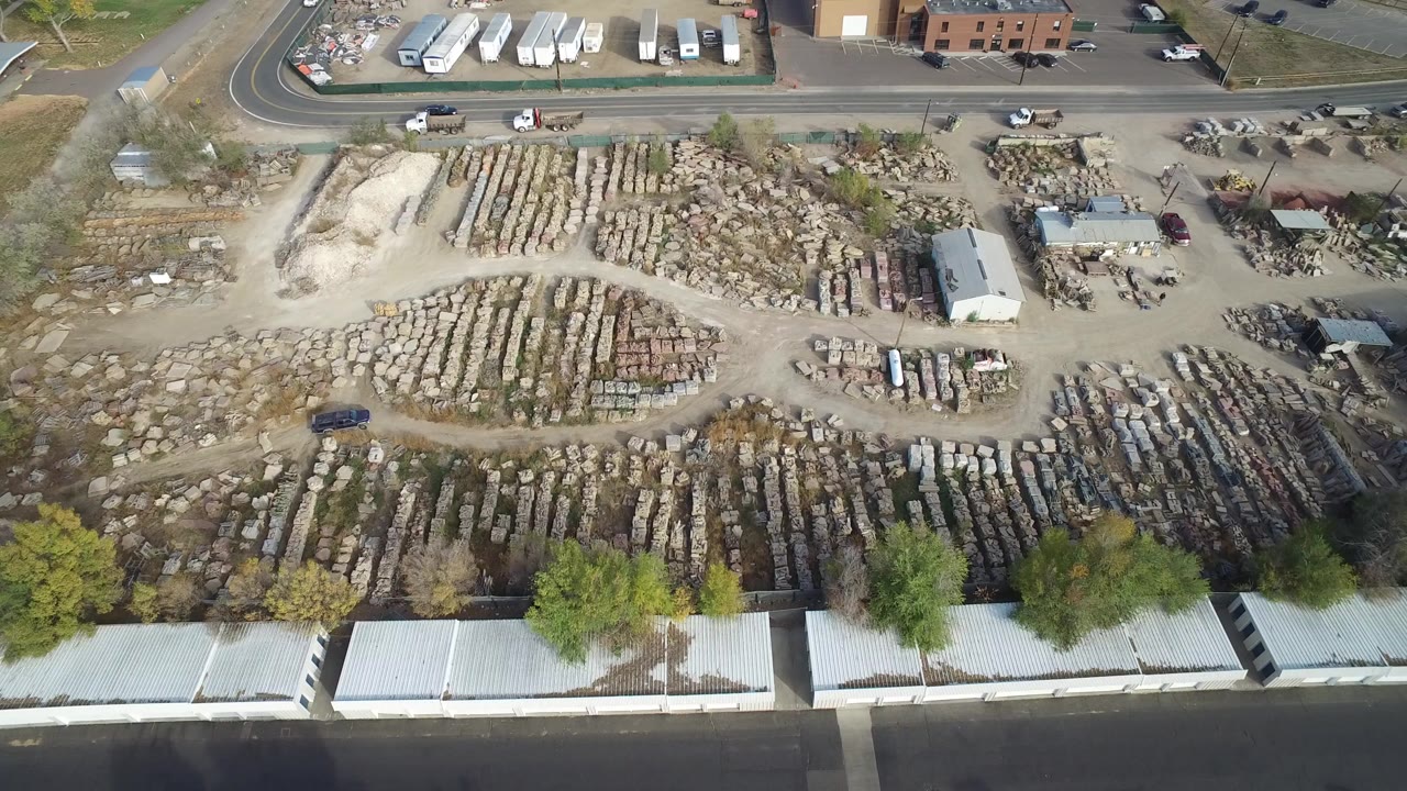 Overhead view of a storage yard beside a road and rooftops.