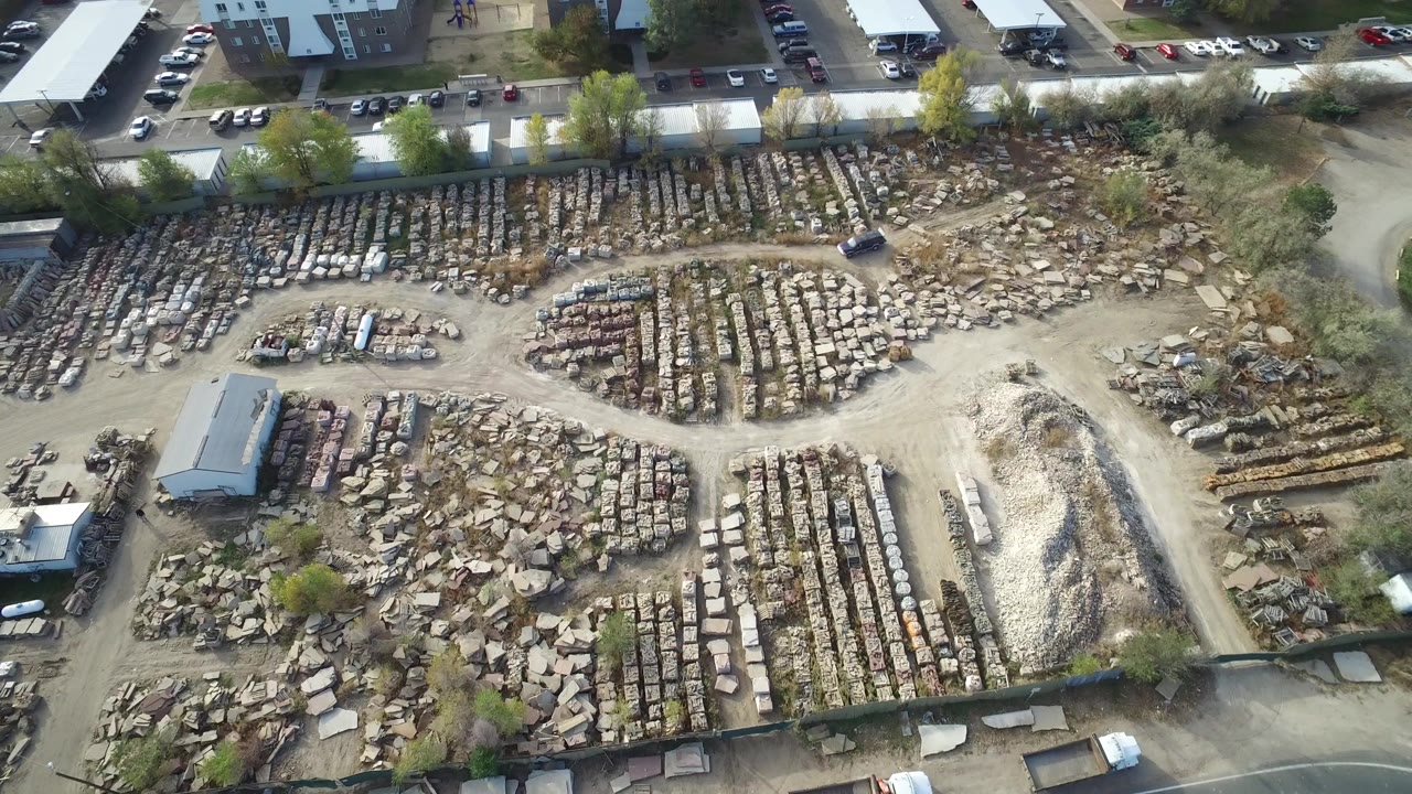 Aerial view of an outdoor stone yard with dirt lanes and nearby parked cars.