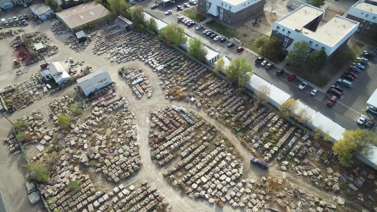 Aerial view of rows of stone materials beside industrial buildings and roads.