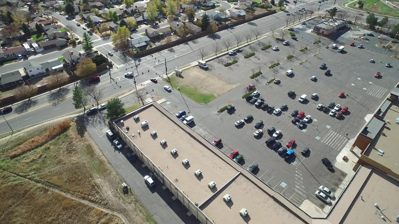 Aerial view of a parking lot beside a flat-roofed building and residential streets.