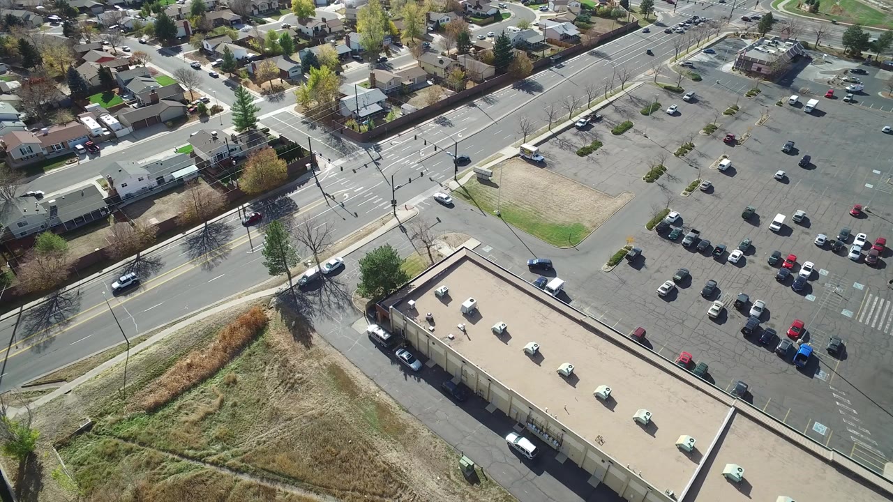 Aerial view of suburban intersection beside a parking lot and low buildings.