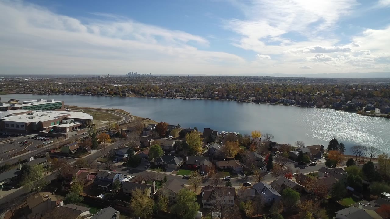 Aerial view over homes, water, shoreline buildings, and distant skyline