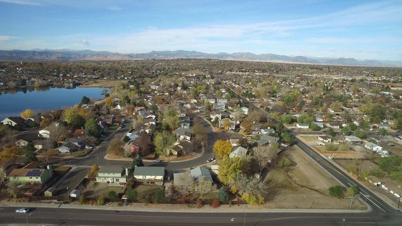 Aerial view of homes, roads, lake, trees, and distant mountains.