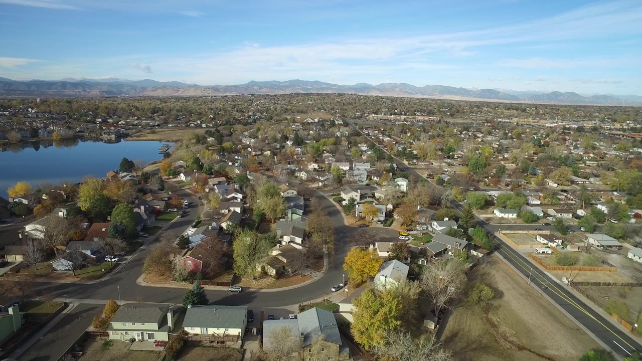 Aerial view of homes, roads, a lake, and distant mountains.