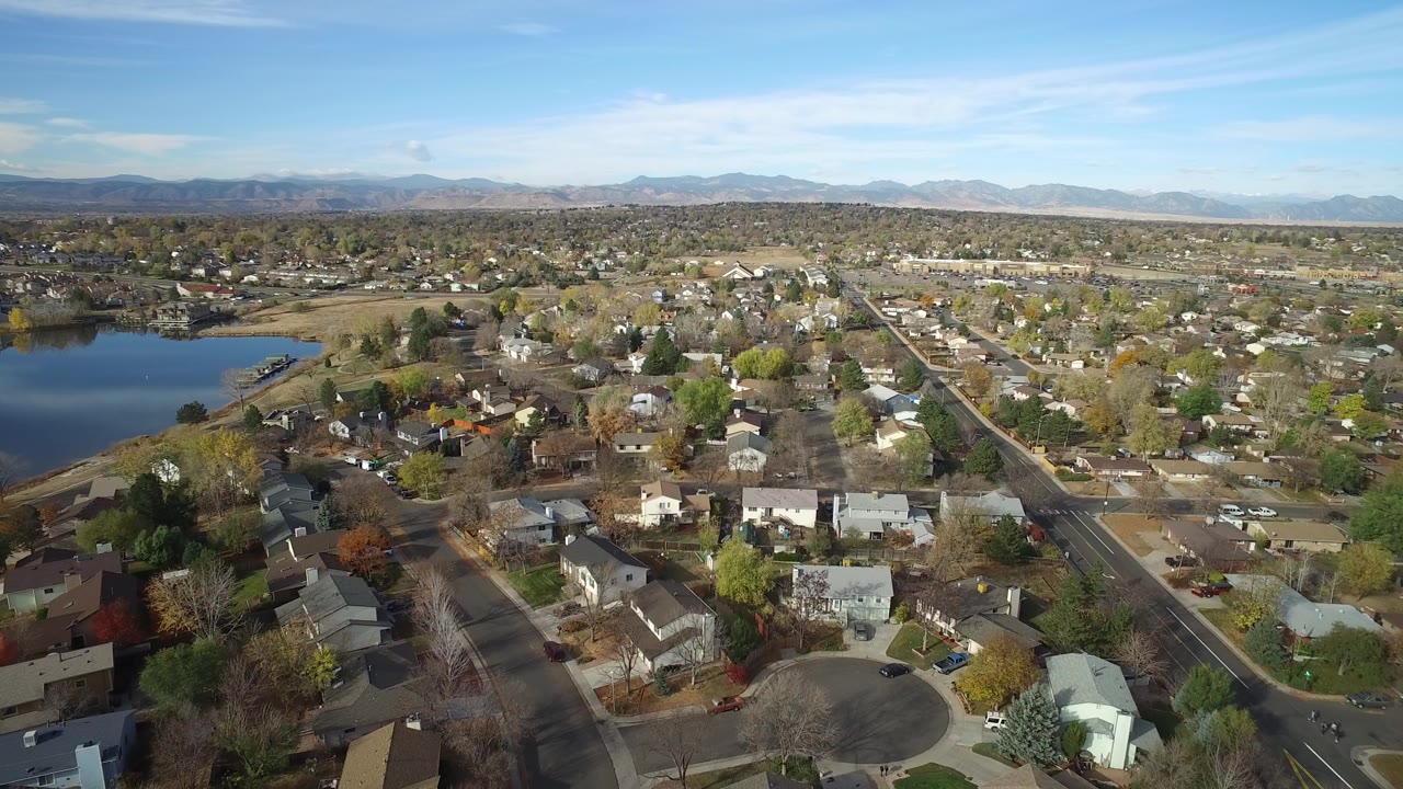 Aerial view of a residential neighborhood beside a lake with mountains in the distance.