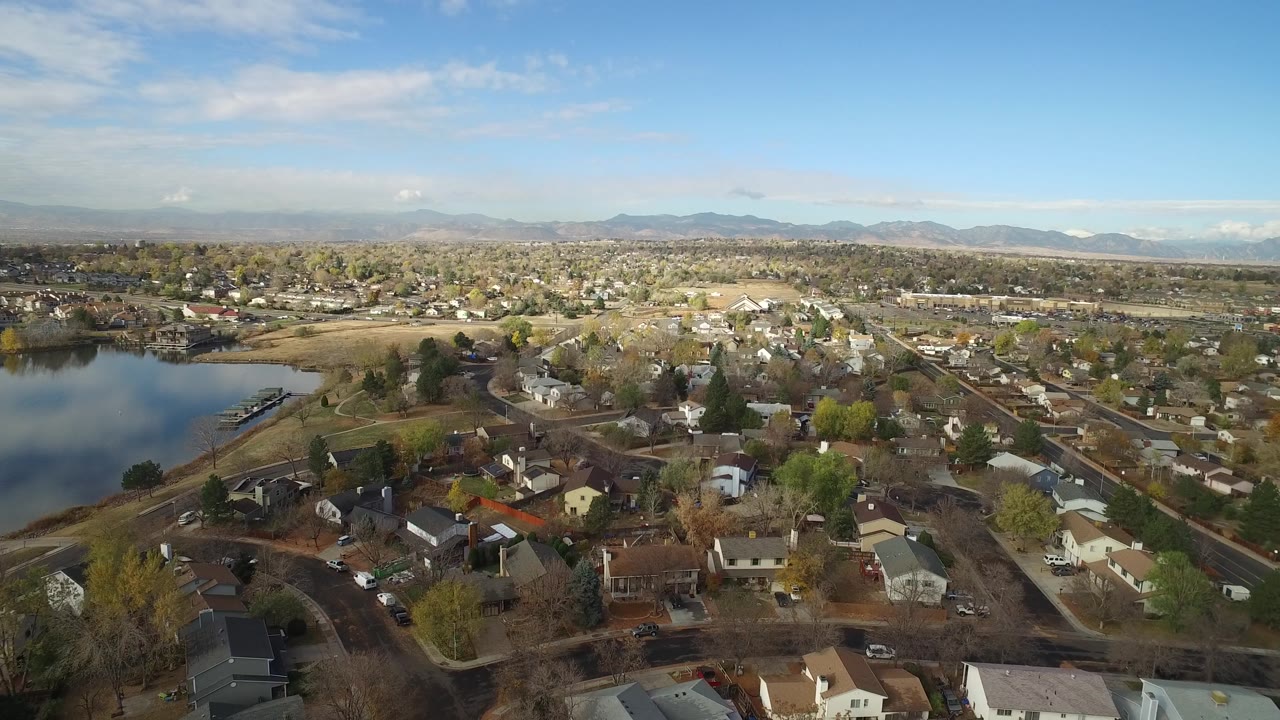 Residential rooftops near a reflective lake under blue sky.