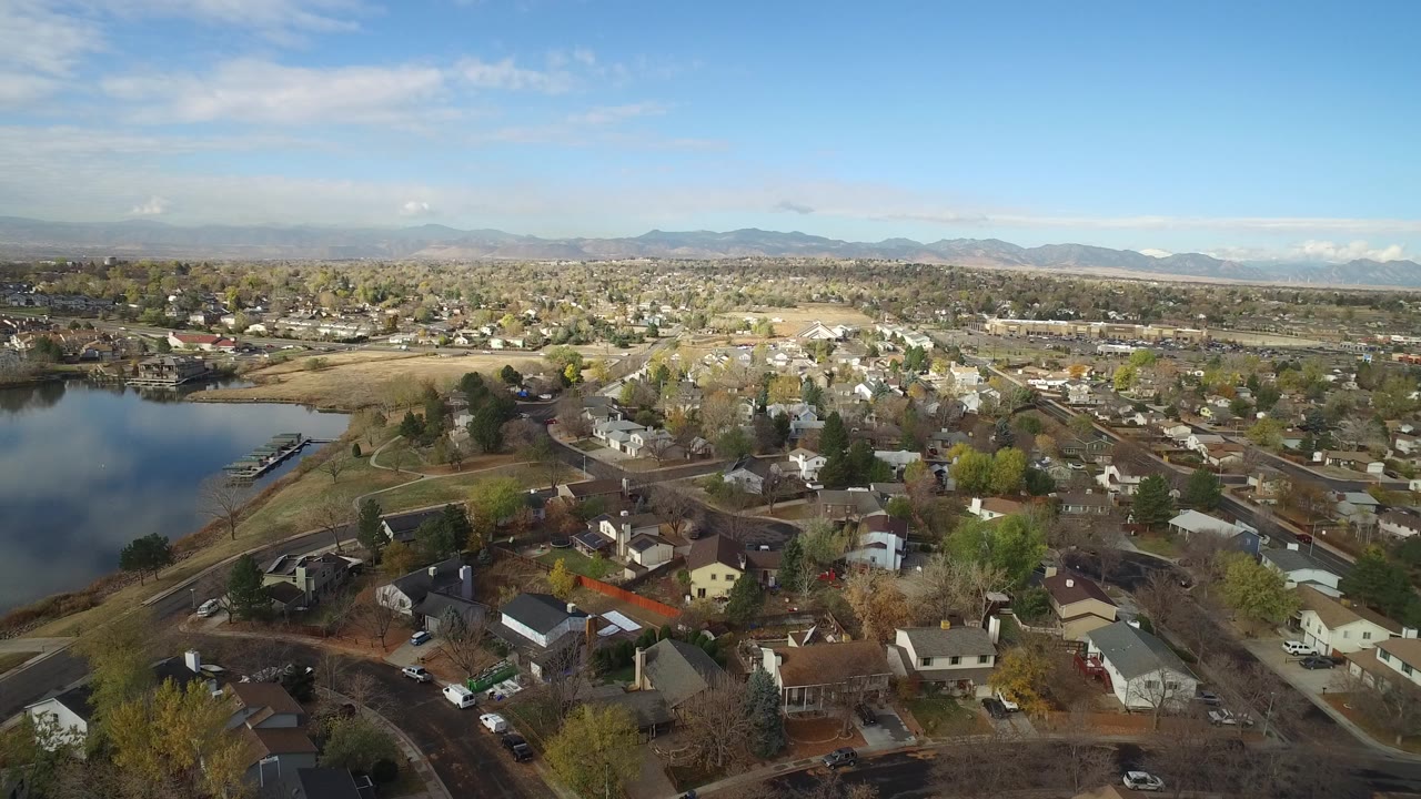 Aerial view of houses, streets, trees, lake, and distant mountains