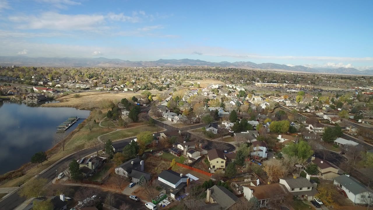Aerial view of lakefront homes, roads, and distant mountains.