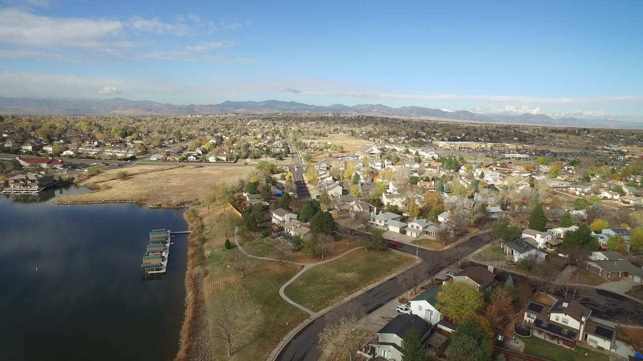 Drone-height view of Hidden Lake shoreline, docks, houses, streets, and mountain horizon.