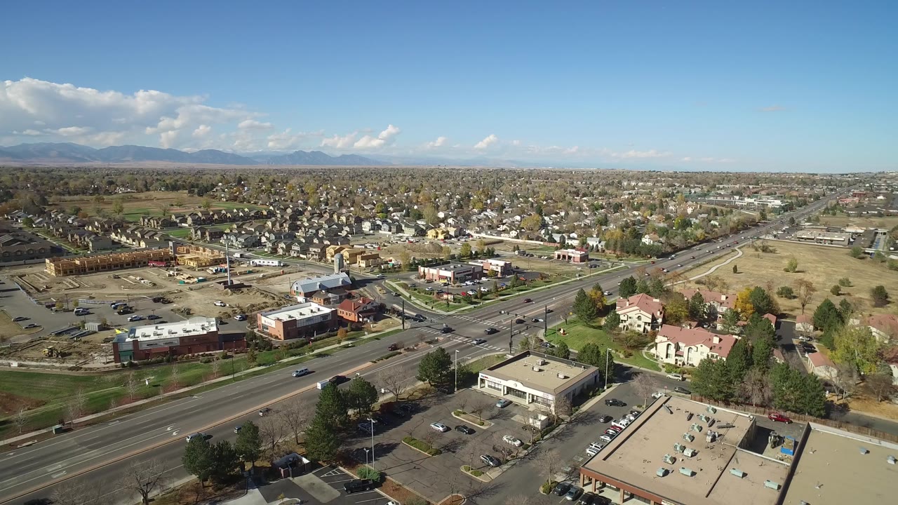 Aerial view of suburban roads, houses, businesses, and distant mountains.