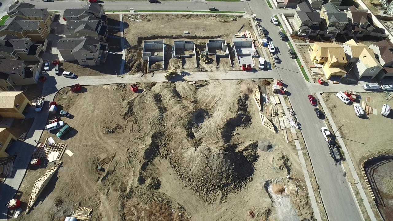 Aerial view of residential construction lots beside paved streets and houses.