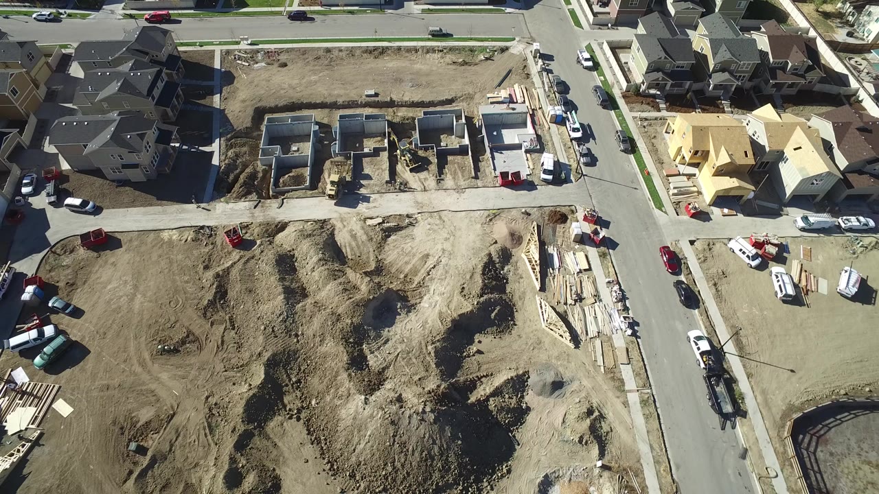 Aerial view of houses, dirt lots, streets, and active residential construction.
