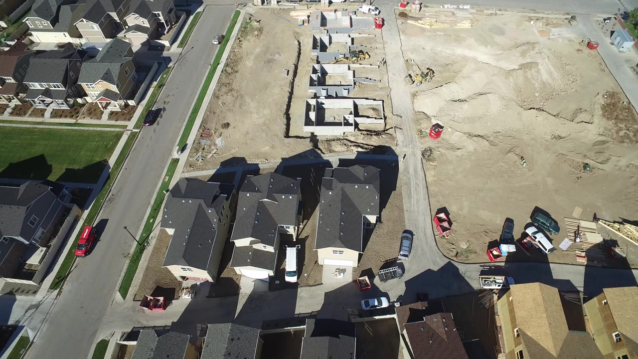 Aerial view of home foundations beside a suburban street and finished houses.