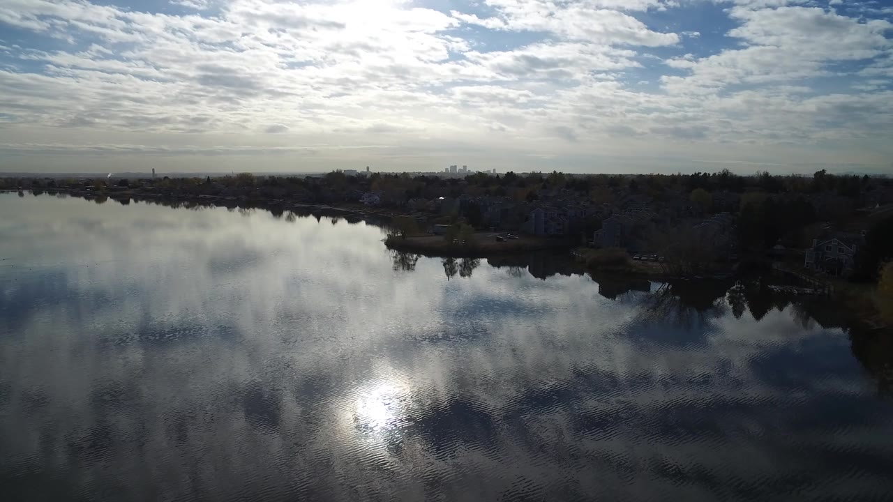 Reflective lake surface with bright sky above a dark shoreline.