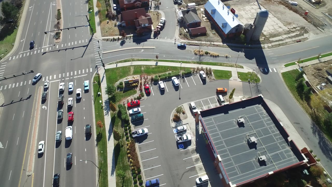 Aerial view of a multilane road beside a parking lot and low buildings.