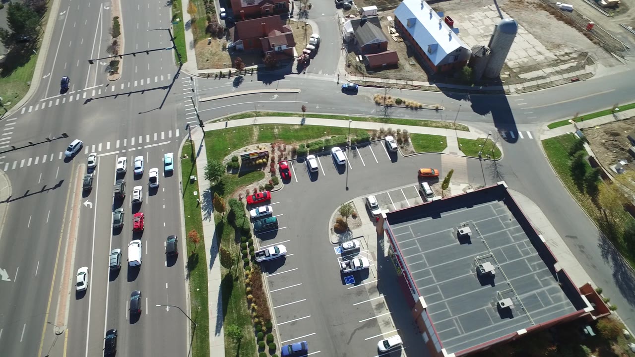 A second Hidden Lake, Colorado overhead frame shows cars moving and parked near a small parking lot, landscaped grass, sidewalks, and no visible people.