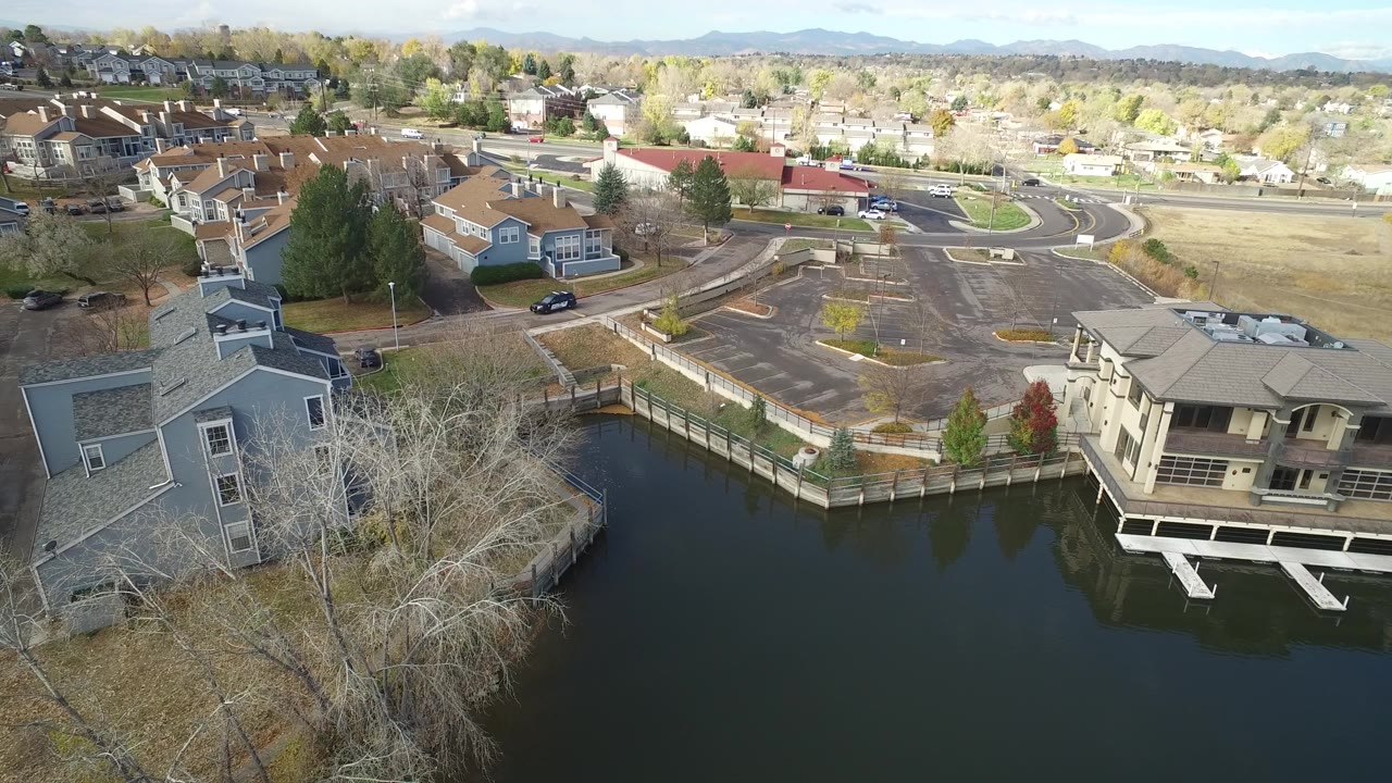 Drone view across residential buildings, water, roads, and distant hills.