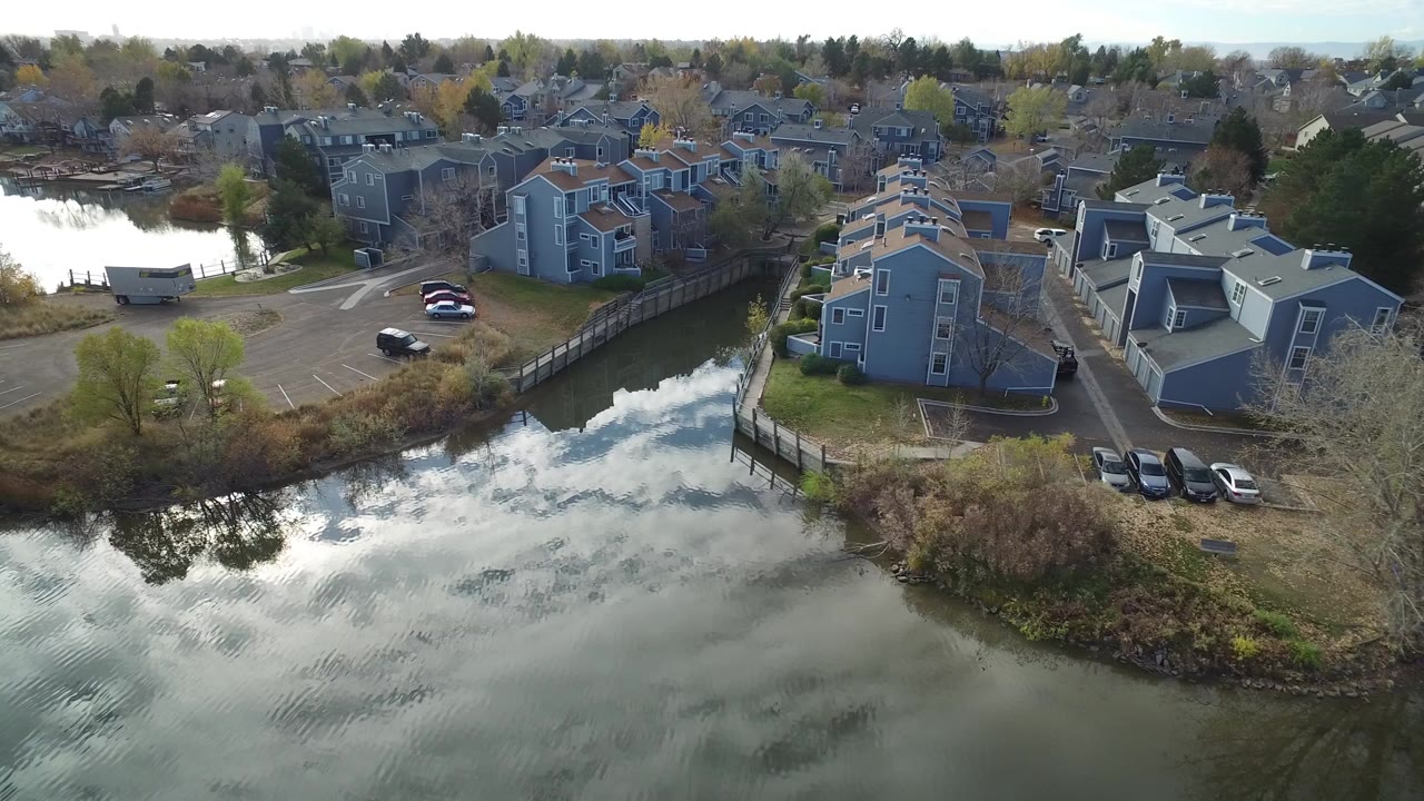 Aerial view of lakeside townhomes, parking, and reflective water.