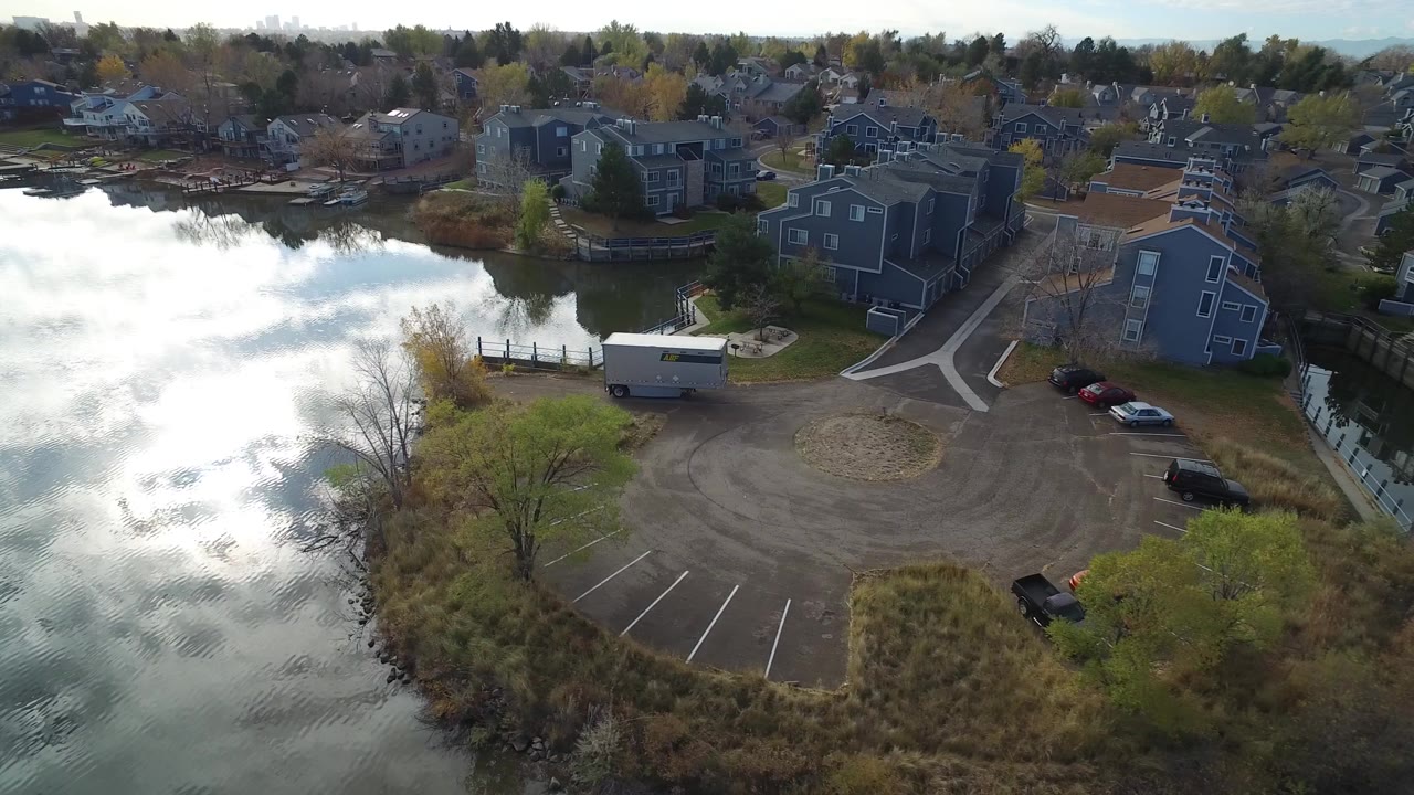 Aerial view of lake water beside shore homes and a parking area.