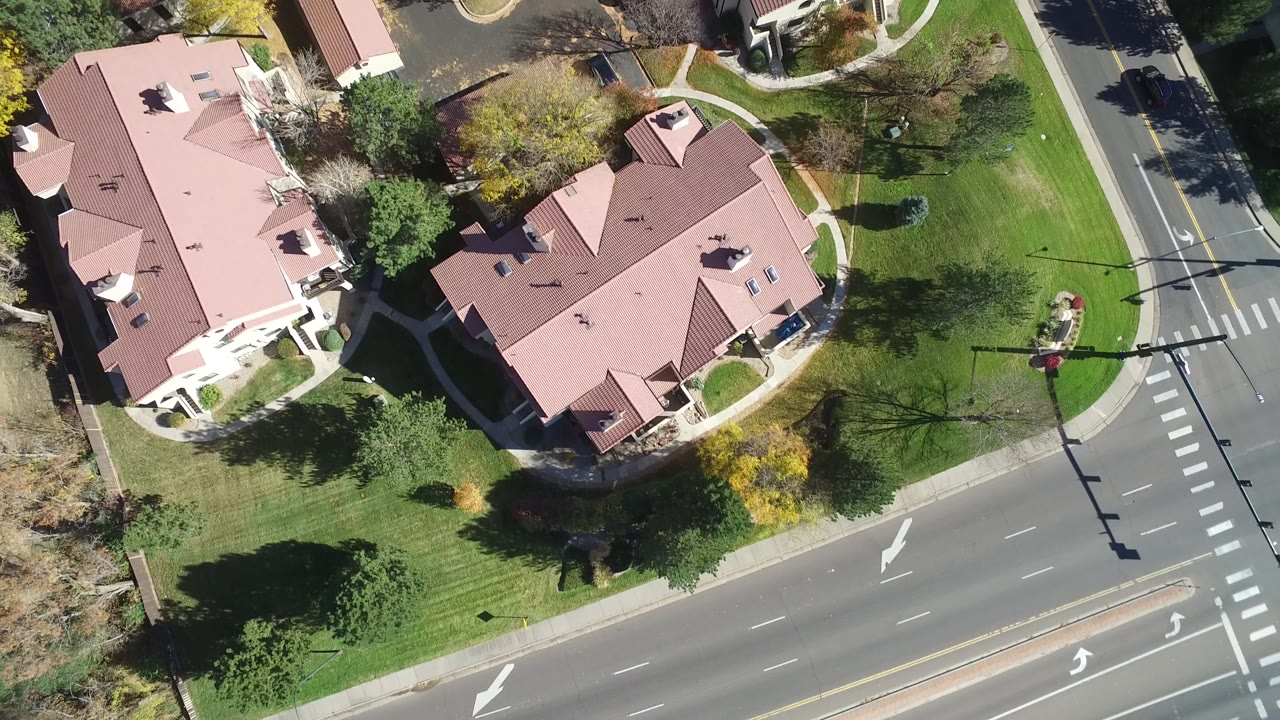 Top-down aerial view of red-roofed homes beside a road and lawns.