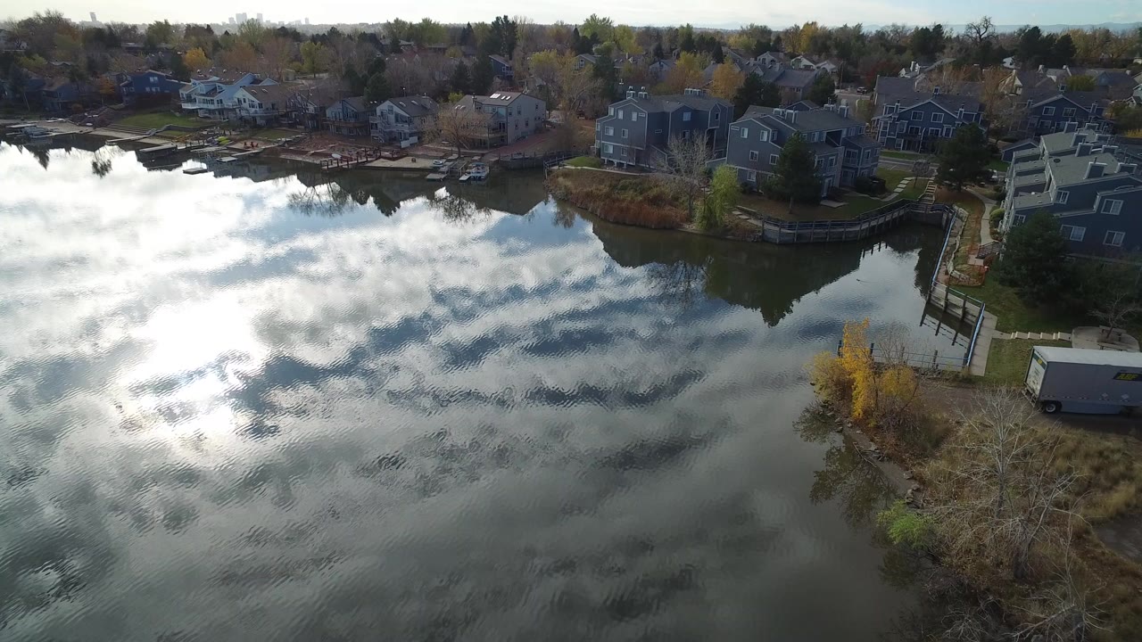 Aerial view of a reflective lake beside shoreline houses.