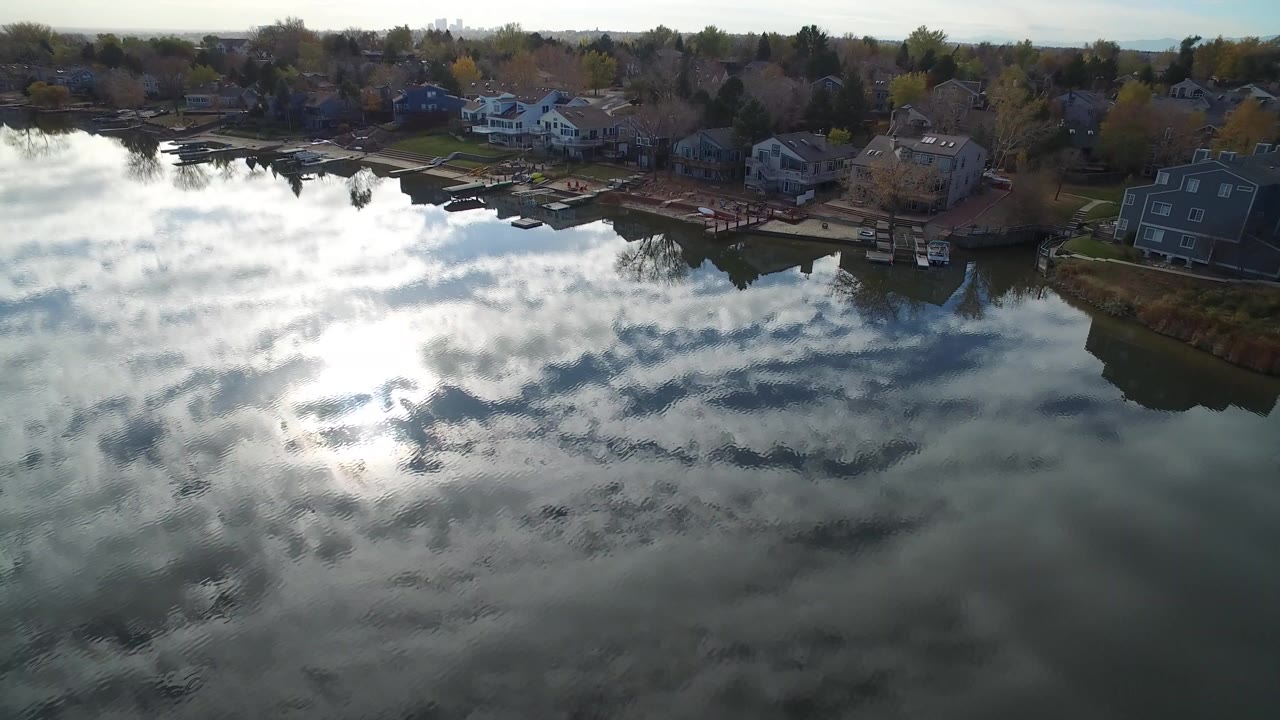 Aerial view of a reflective lake beside shoreline homes and docks.