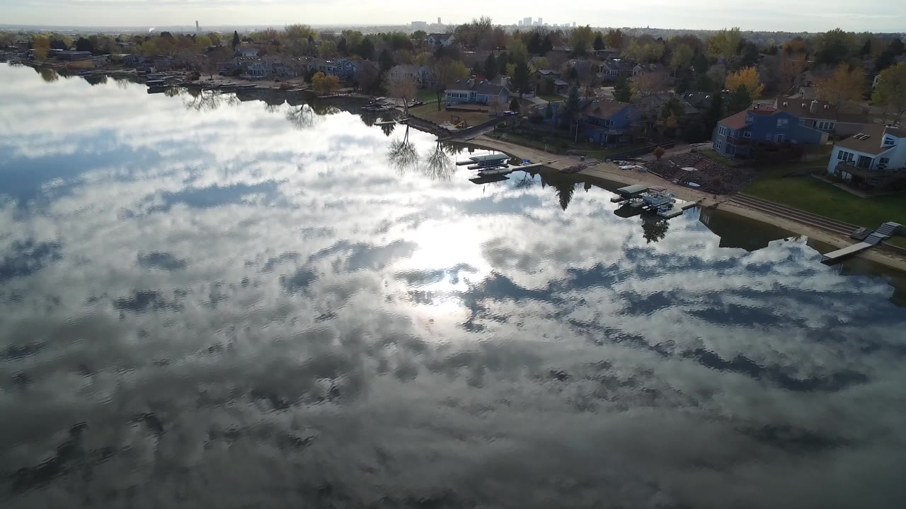 Residential lakefront seen above mirrored clouds on calm water