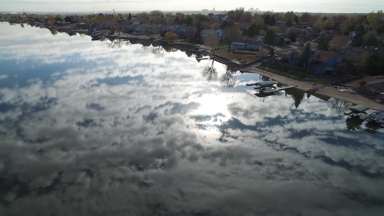 Aerial view of reflective water beside shoreline houses and docks.