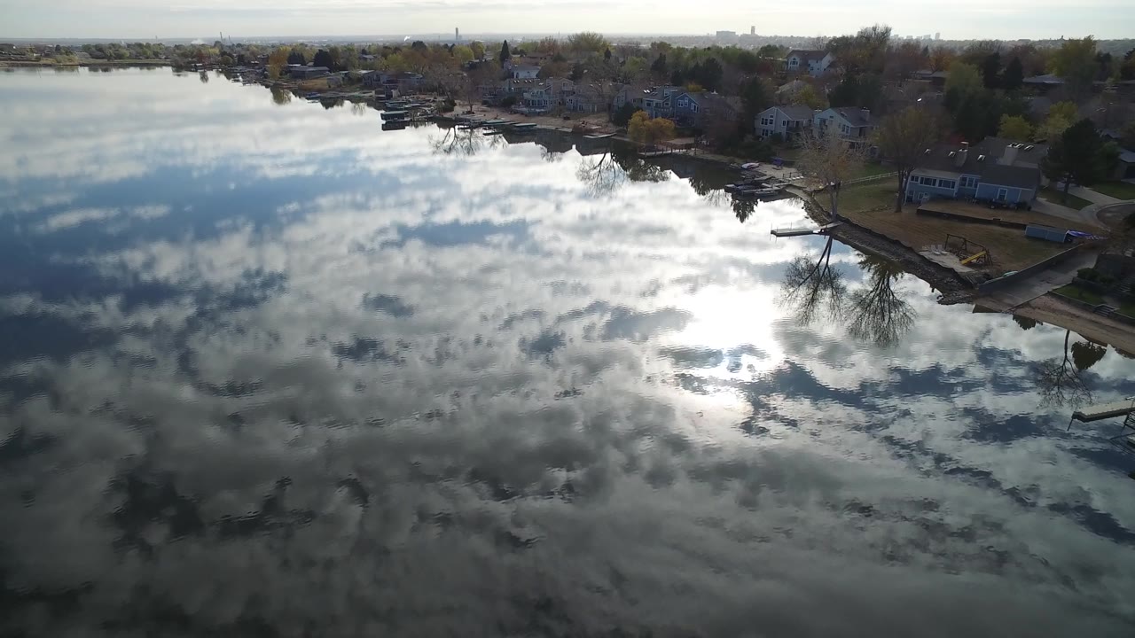Wide aerial lake view with a residential shoreline and distant horizon.
