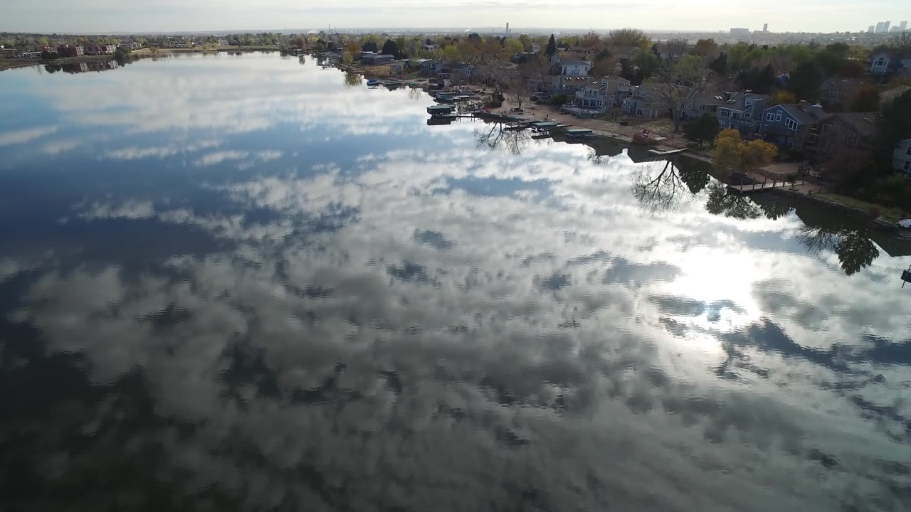 Hidden Lake, Colorado shoreline remains across the upper frame while bright cloud reflections spread across the darker water, with no visible people.