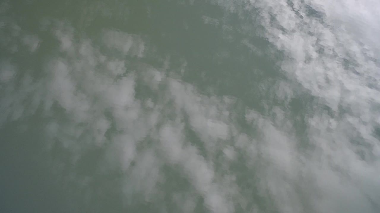Cloud reflections on green-gray lake water