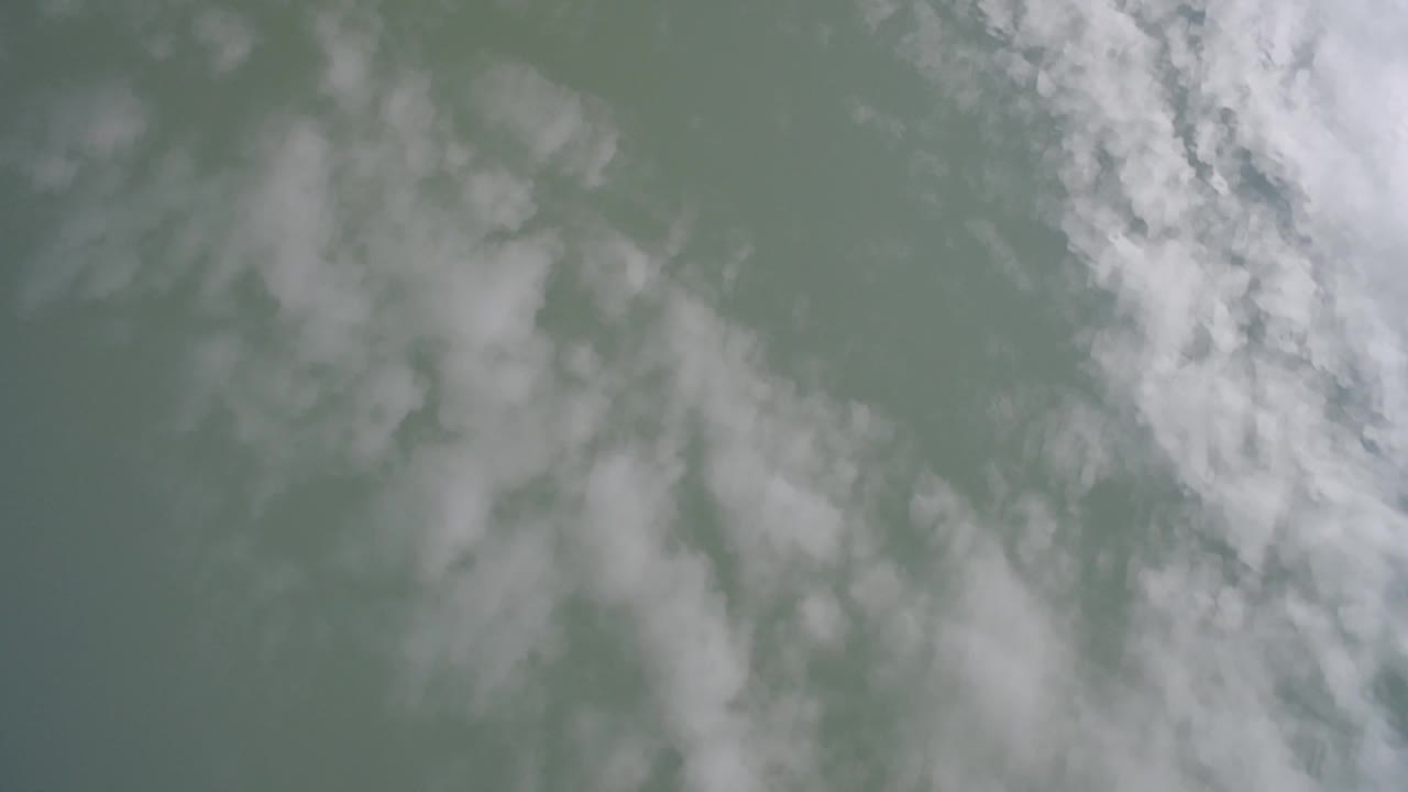 At Hidden Lake, Colorado, pale white clouds reflect across a green-gray water surface with no visible people or shoreline.