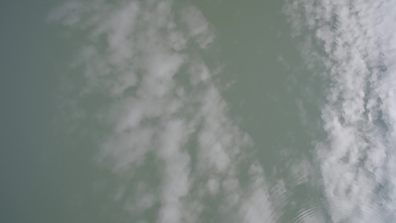 A soft cloud reflection spreads across the Hidden Lake water surface as small ripples lightly break the reflection, with no visible people.