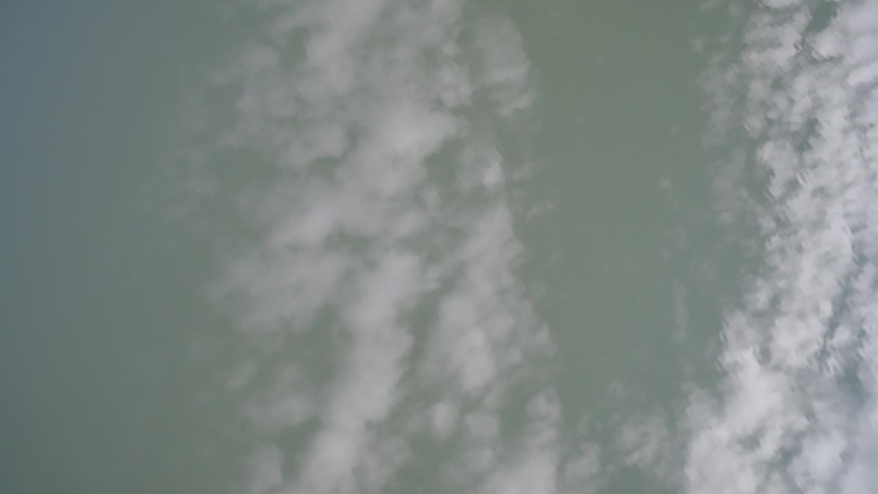 Opening frame of pale blue-green sky over Hidden Lake Colorado with broad white cloud bands and no visible people.