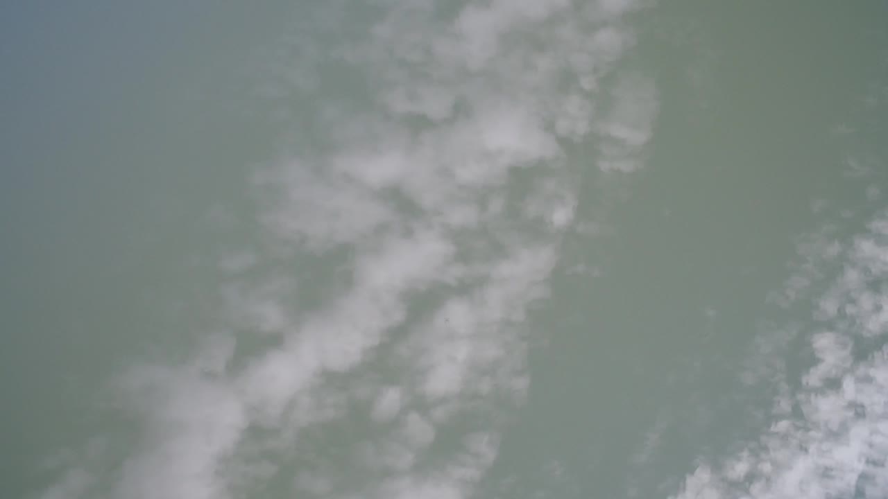 Green water at Hidden Lake, Colorado, with a larger cloudy white patch near the center of the frame and no visible people.