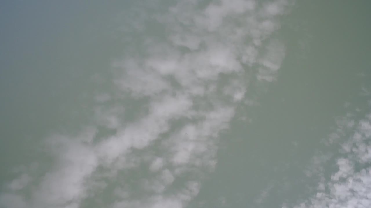 Soft scattered clouds across a pale blue-green sky.