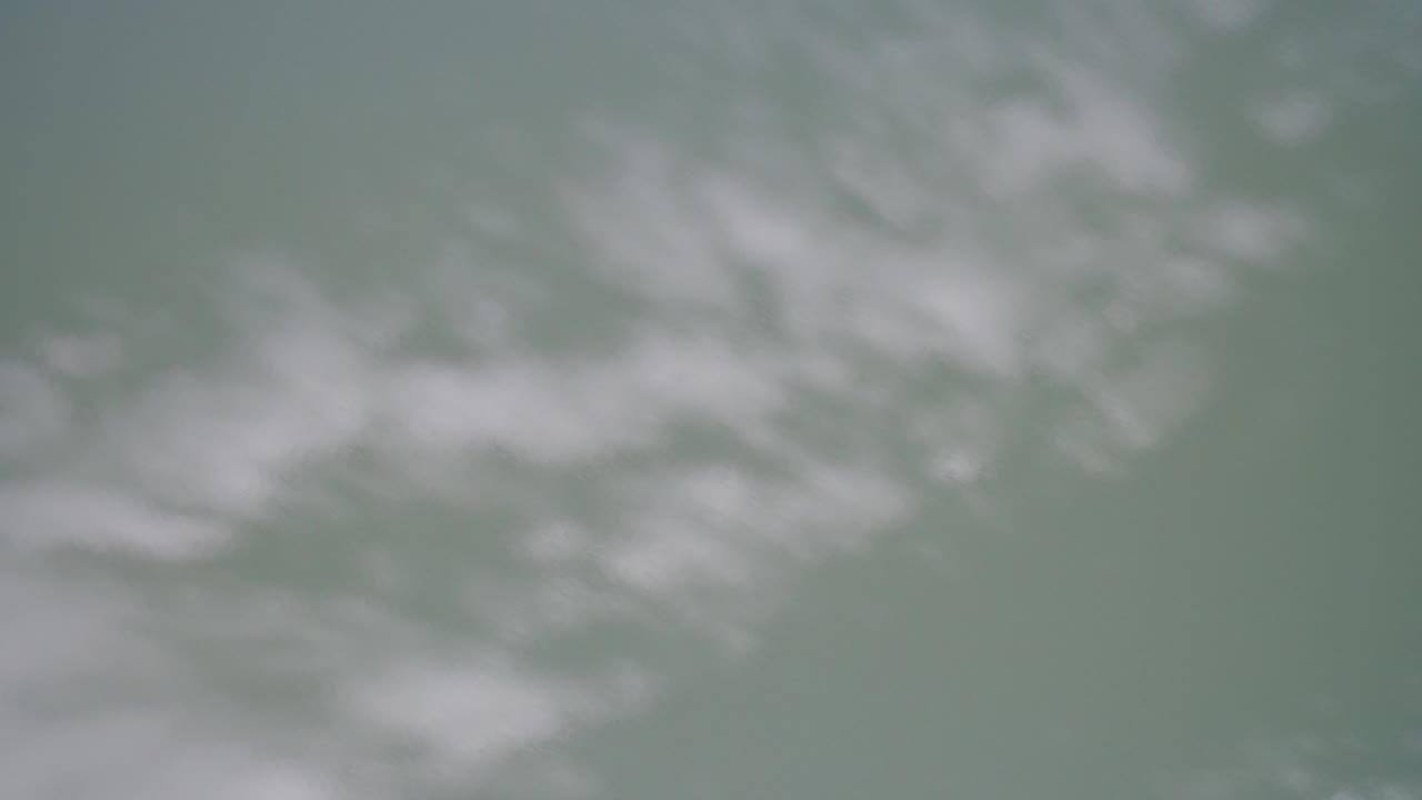 Soft white cloud shapes over a muted green-blue field.