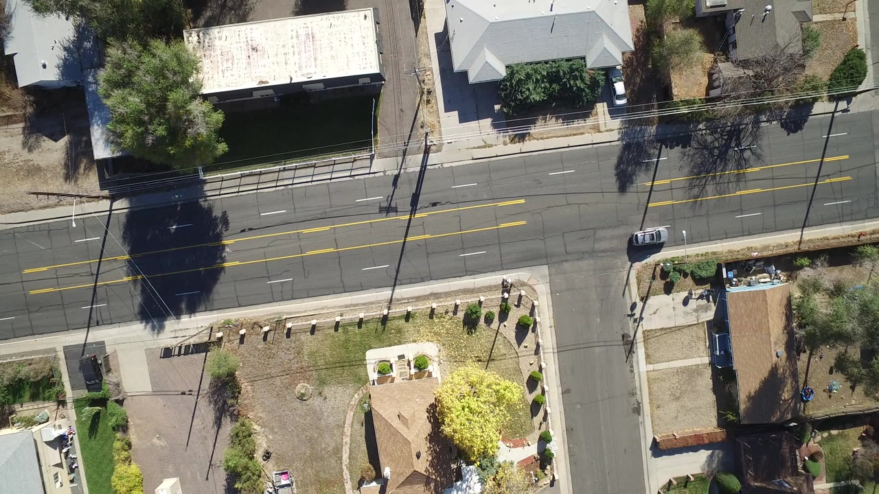 Overhead view of a residential road, homes, sidewalks, and tree shadows.