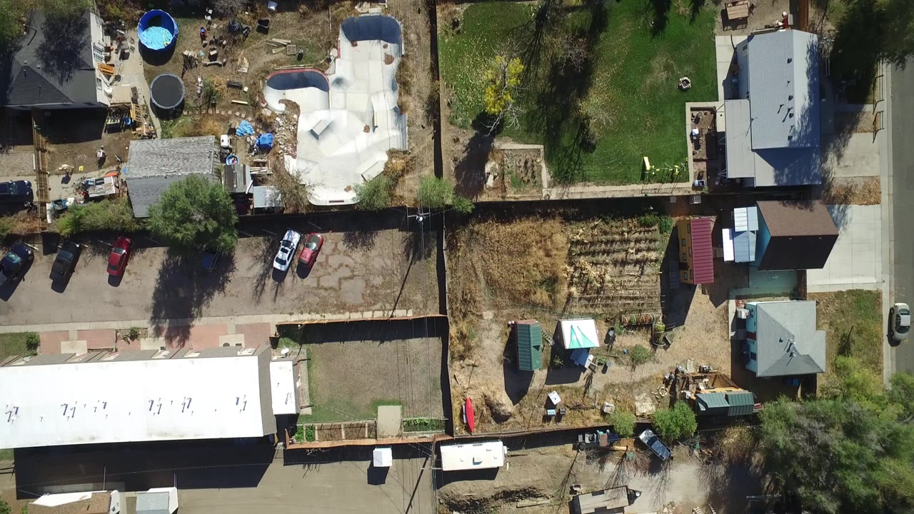 Top-down aerial view of homes, yards, pools, cars, trees, and fences.