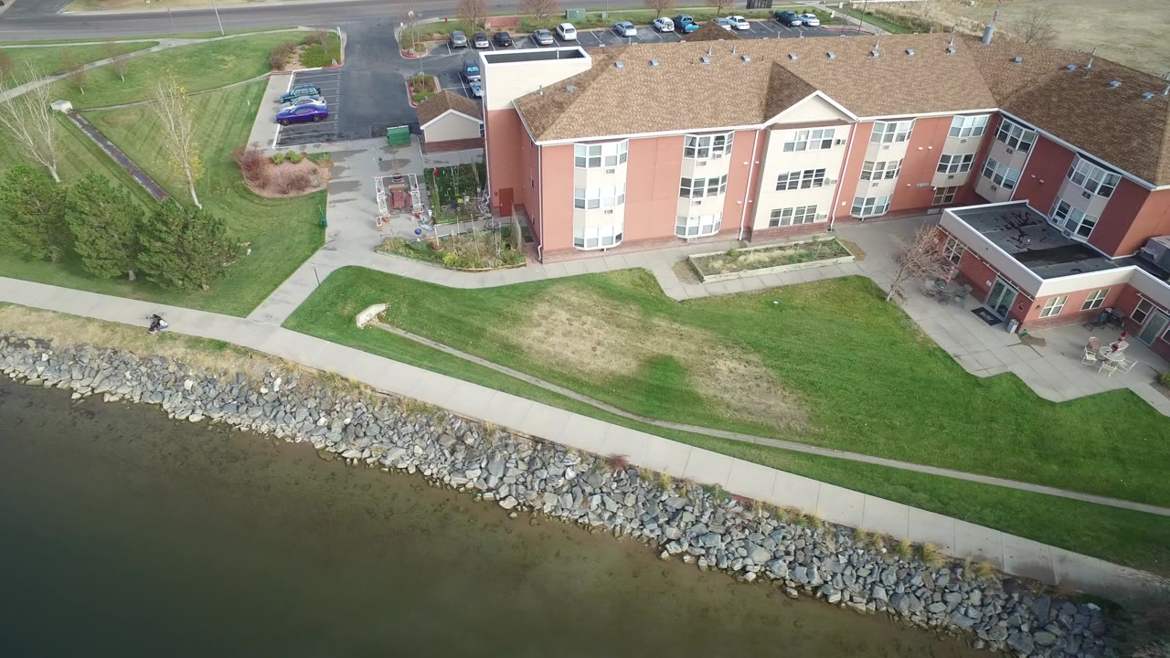 Aerial view of a low-rise building beside shoreline rocks and water